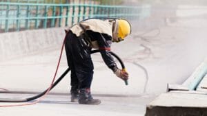 Bauarbeiter strahlt Bodenfläche mit Trockeneisstrahler